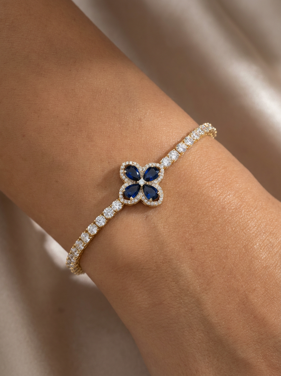 Emily Bileklik, merkezde safir mavisi zirkon taşlar ve altın kaplama detaylarıyla şıklığı ve zarafeti simgeliyor. Her tarza uyum sağlayan lüks bir aksesuar.